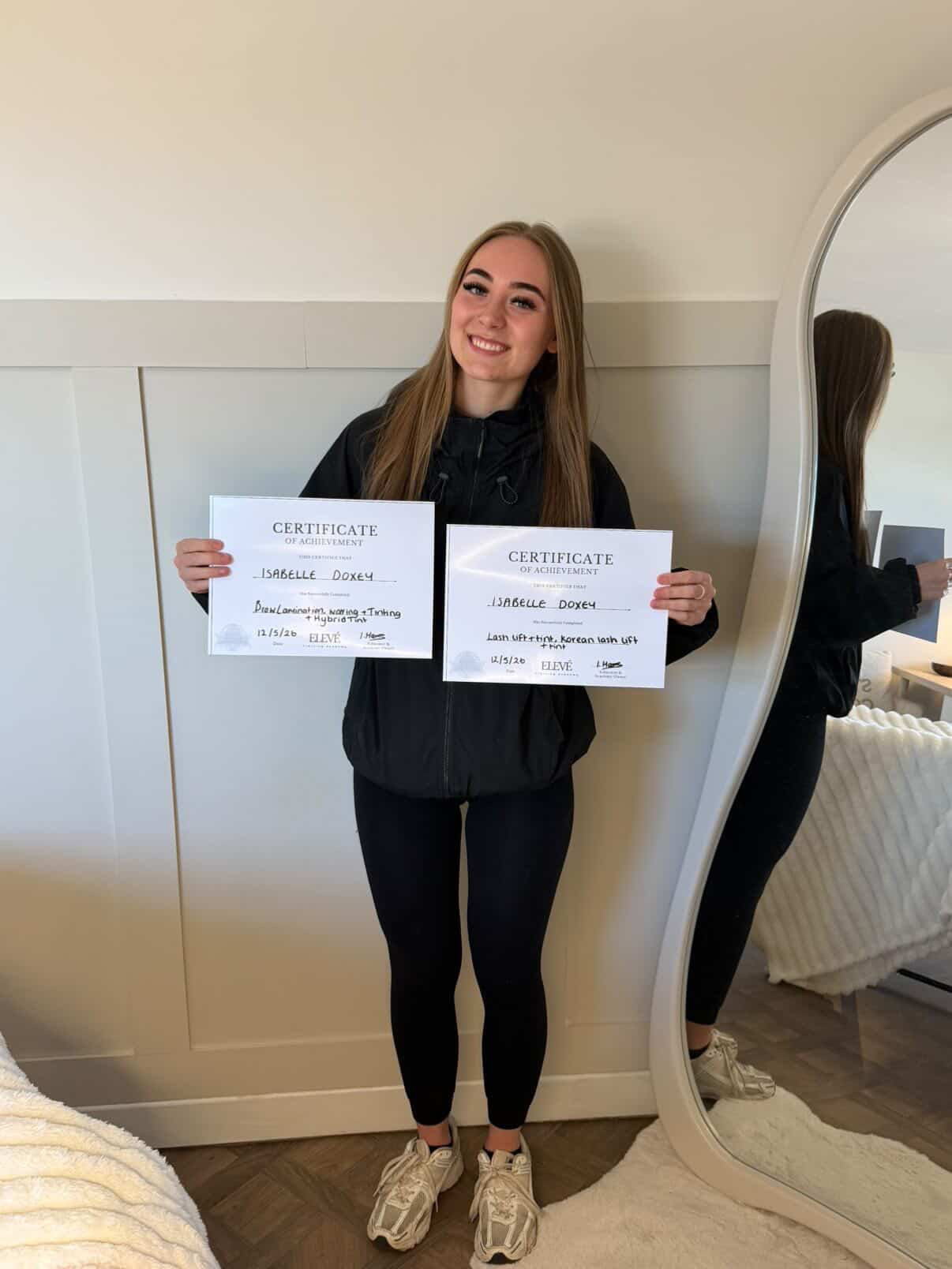 Isabelle Doxey holding brow and lash training certificates